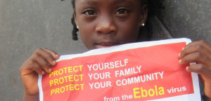 A small child holds a sign about protecting yourself from Ebola virus.